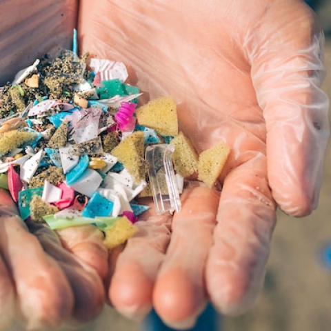 Hands holding colourful microplastic waste
