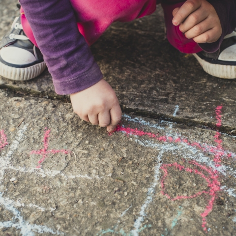 Child drawing with chalk on pavement