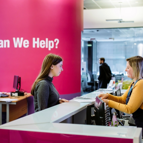 Female student standing at careers and employability help desk