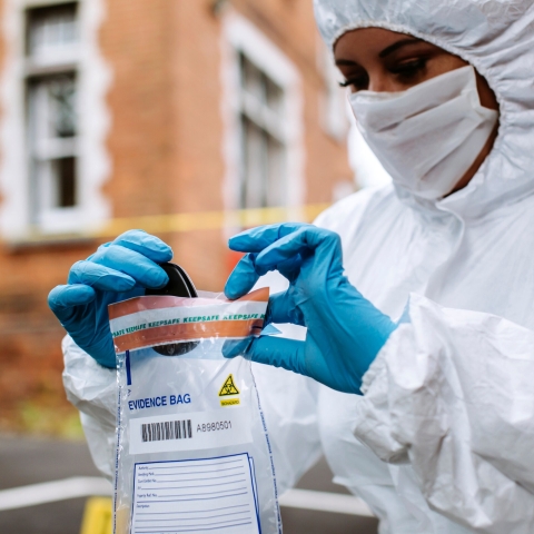 Forensic at crime scene handling keys into evidence bag