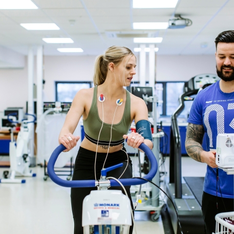 Person using an exercise bike with ECG monitoring