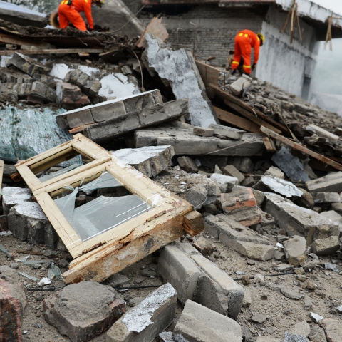 two people in high visibility suits searching through a pile of rubble and debri