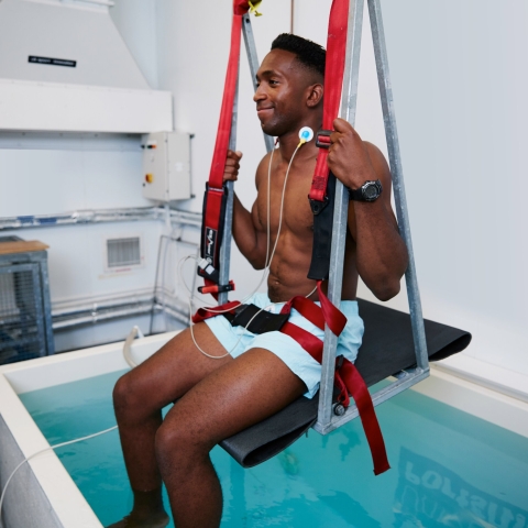 A man in a harness being submerged in water