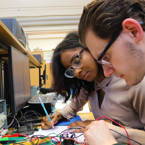 Two students working on an electronic engineering project added