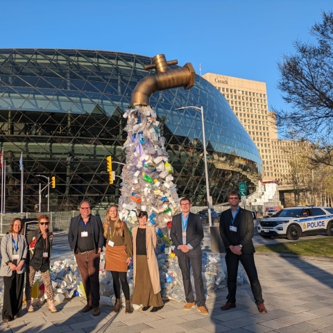 Revolution Plastics Institute team beside the plastic tap sculpture at INC-4 in Ottawa