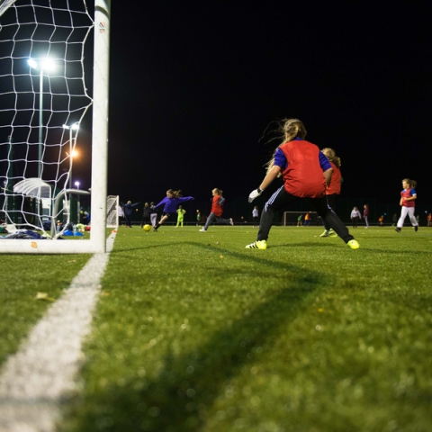 Goalkeeper defends a goal during a night-time football match