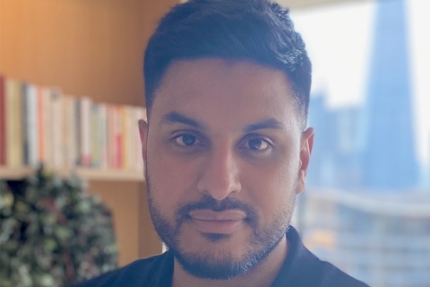 A headshot of Abbas Kanani looking to the camera wearing black polo shirt