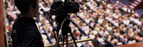 Person filming graduation ceremonies from balcony