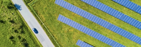 Aerial picture of solar panels in a field, next to a road