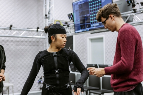 Staff member assisting student with motion capture suit.