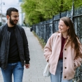 Two students walking down path alongside steel fence talking