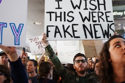 Man holding up a sign saying 'I wish this were fake news'