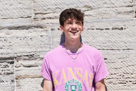 Student in pink shirt stood outside wall