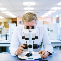 Male student studying in a lab at a microscope